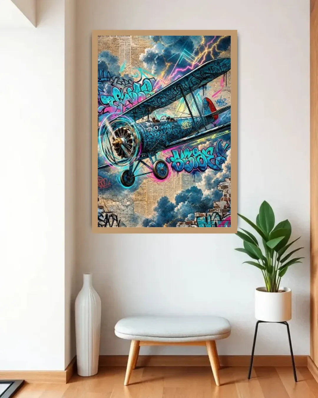 Framed colorful airplane artwork on a wall with a plant and stool below.