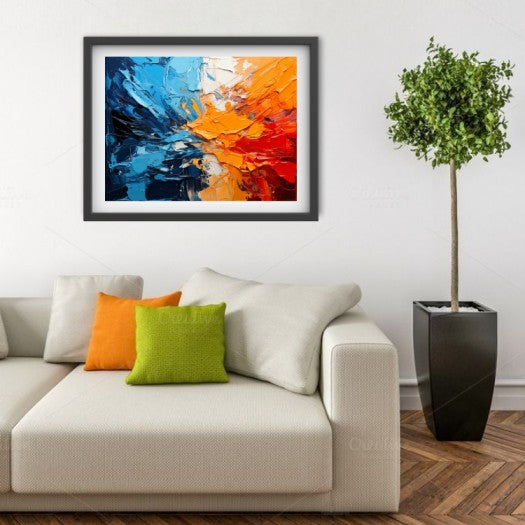 Framed abstract wall art with bold blue, orange, and red brushstrokes, displayed above a cream sofa in a styled living room with accent pillows and a potted tree.