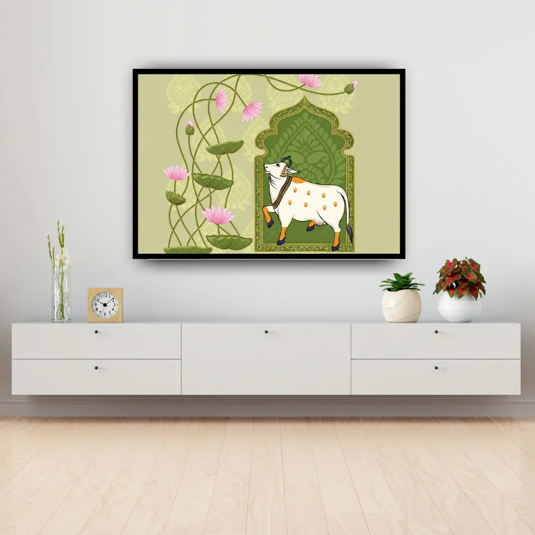 Framed artwork of a cow and lotus flowers on a wall above a white cabinet.