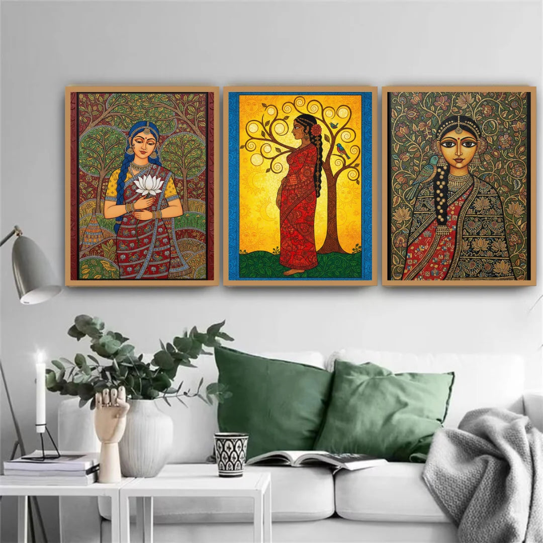 Three framed artworks of women in traditional attire on a wall above a sofa.