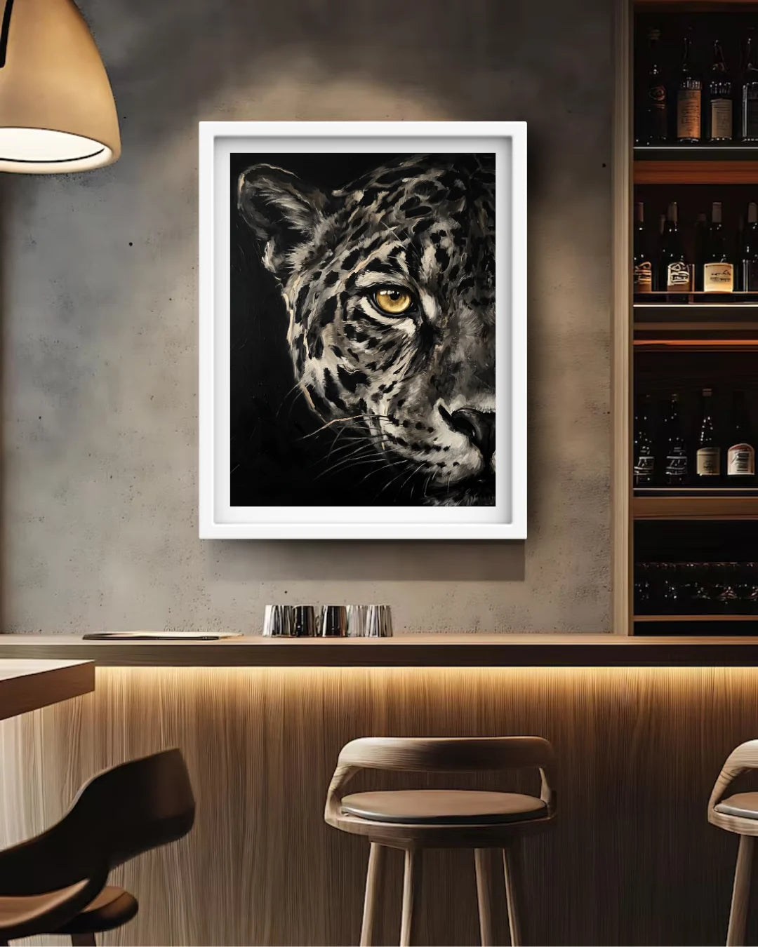 A framed black and white leopard art print with a striking yellow eye, displayed on a textured gray wall above a wooden bar counter in a modern bar setting.