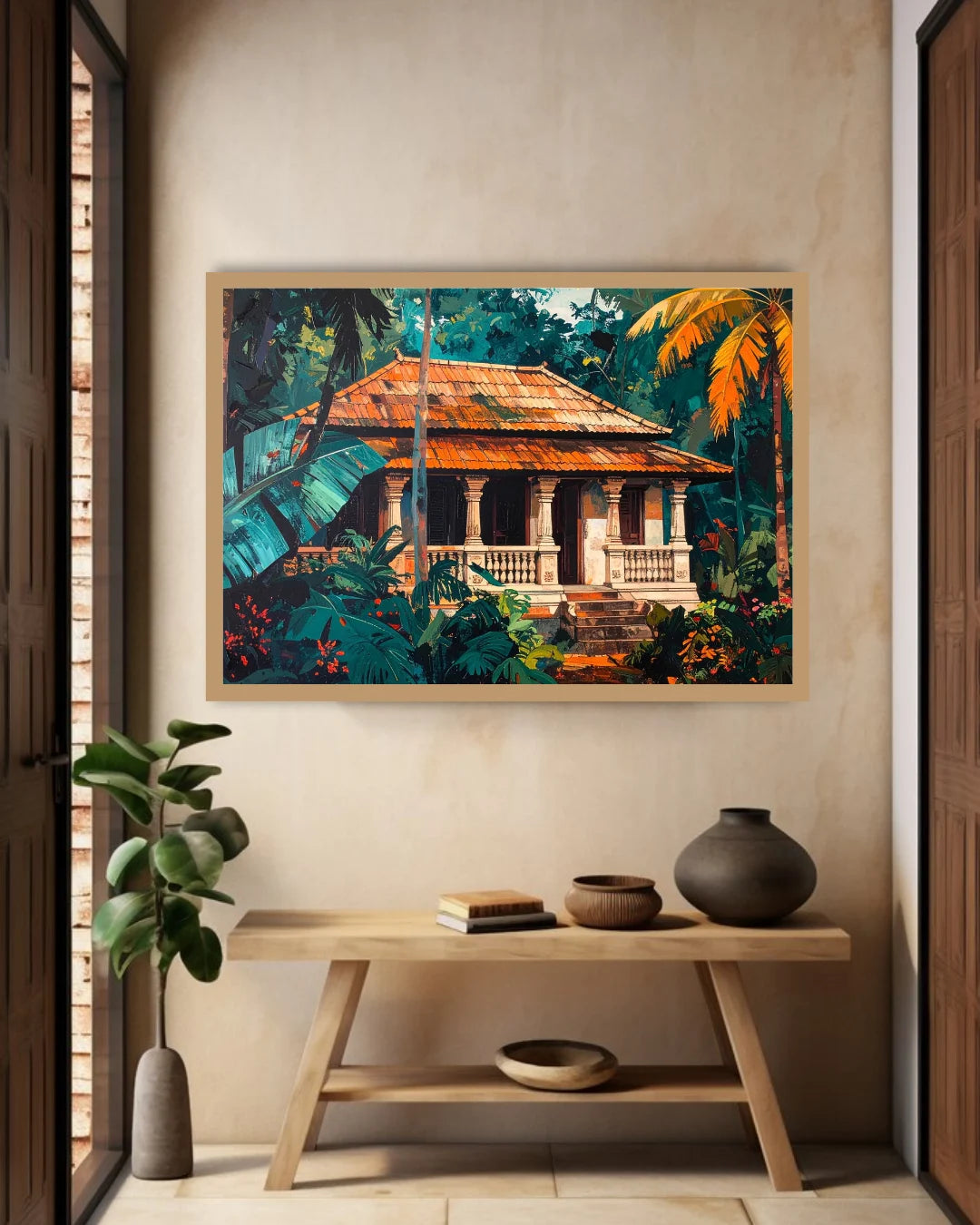 A framed tropical art print depicting a traditional house surrounded by lush green foliage and orange palm leaves, displayed on a beige wall above a wooden console table with decorative vases and books.