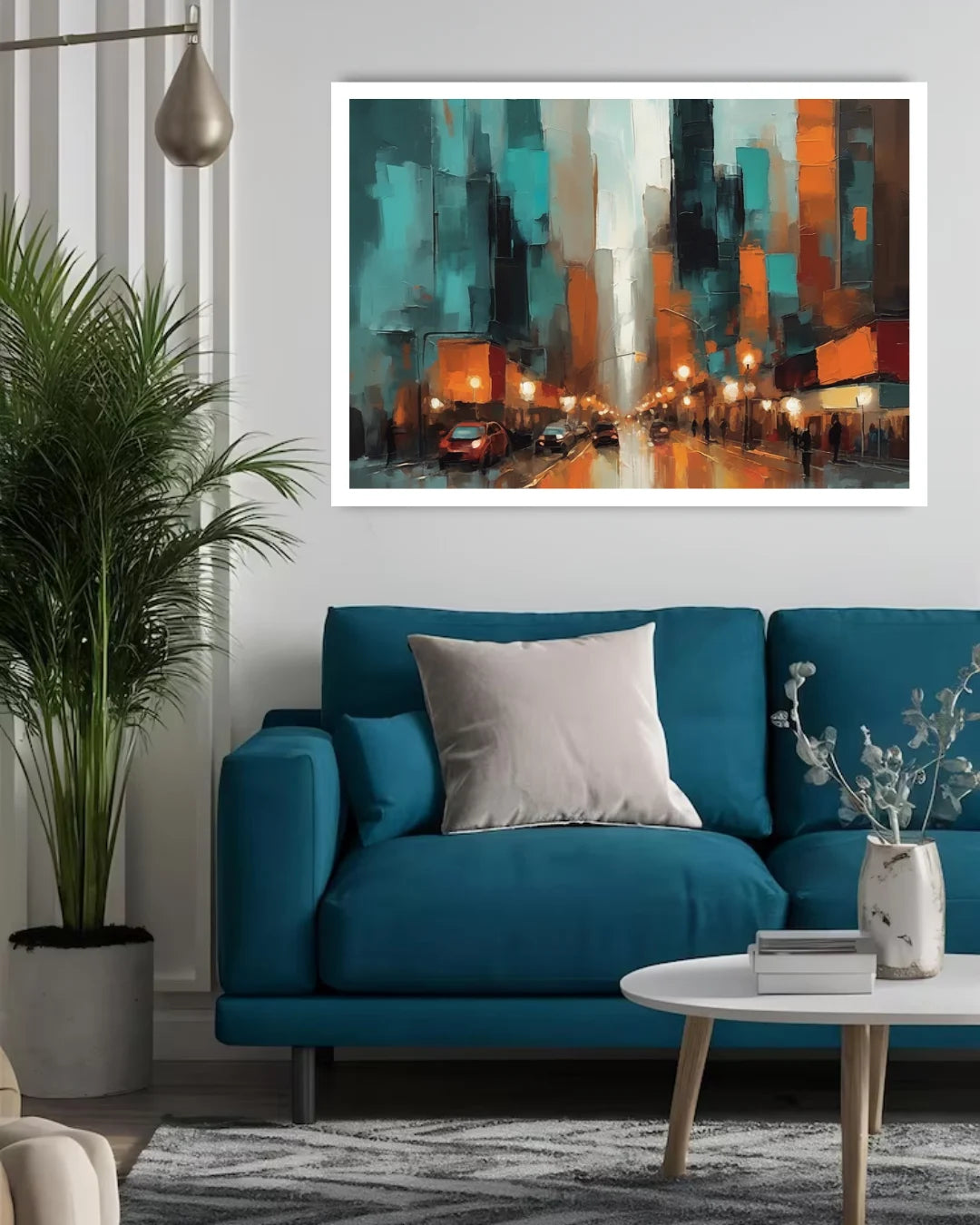 A framed abstract cityscape painting in teal, orange, black, and white hangs on a light gray wall above a blue sofa in a modern living room setting.
