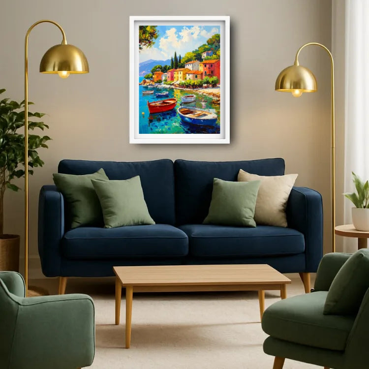 A framed colorful coastal painting with boats and buildings hangs above a navy blue sofa in a styled living room with gold floor lamps, green chairs, and a wooden coffee table.
