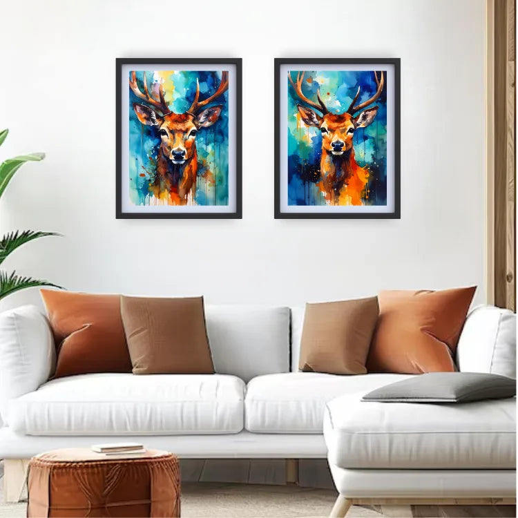 Two colorful deer paintings on a white wall above a white sofa with brown and orange cushions.