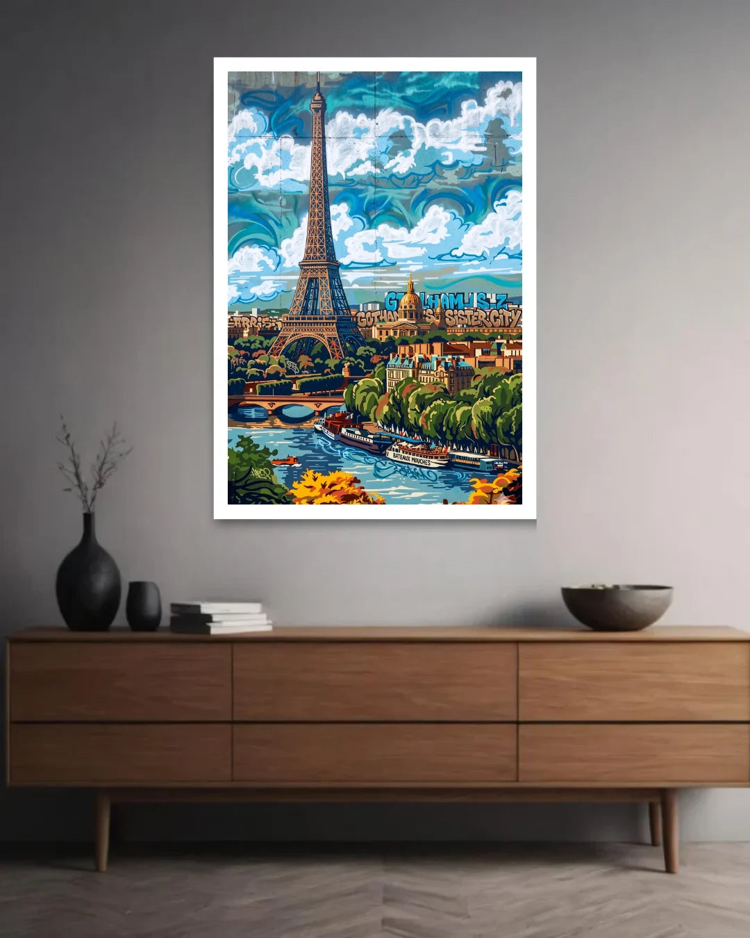 Framed artwork of the Eiffel Tower and Parisian landscape on a wall above a wooden dresser.