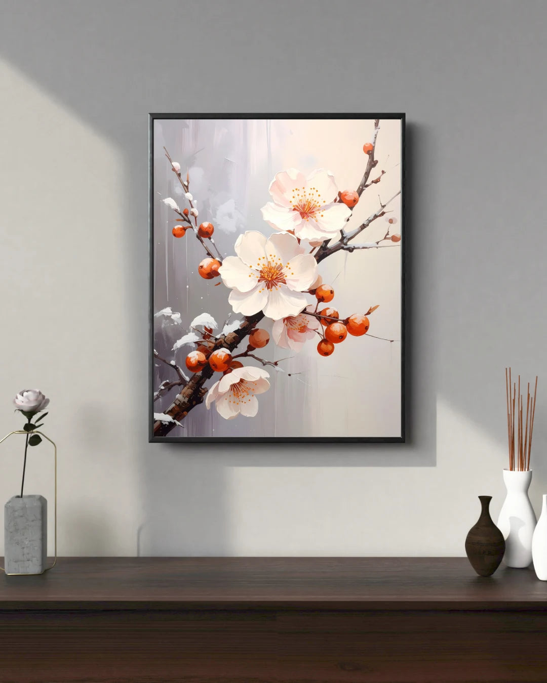 Framed artwork of floral branch with white flowers and red berries on a gray wall.