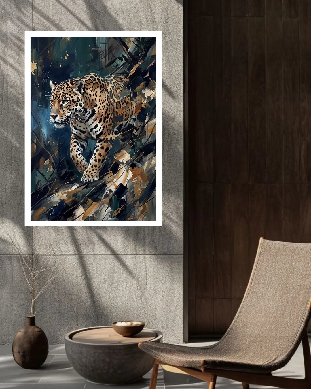A framed wall art print featuring a detailed painting of a leopard in motion, styled in a modern interior setting with a gray stone wall, dark wood paneling, a woven chair, and a small decorative vase.