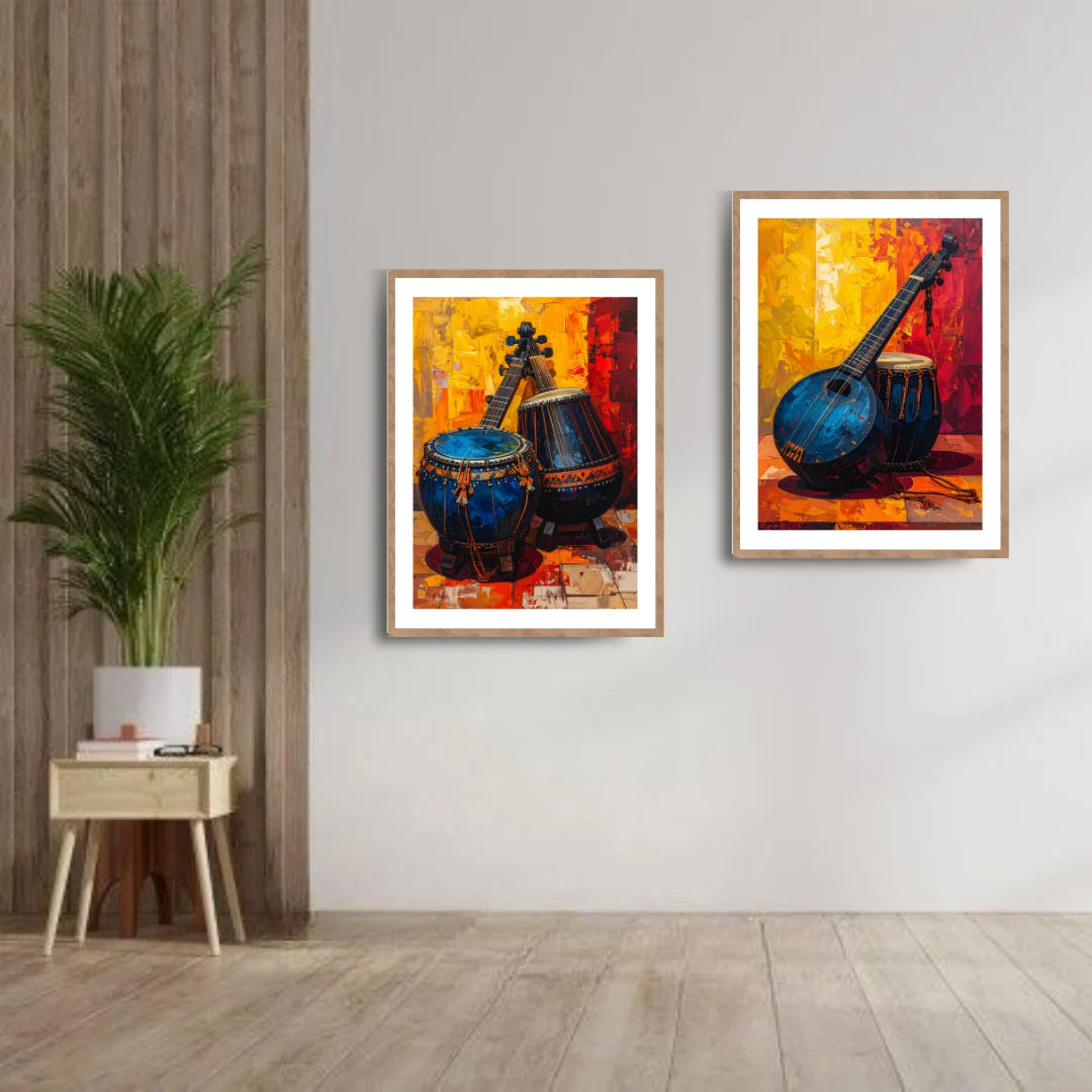 Two framed paintings of musical instruments on a wall with a plant and small table below.
