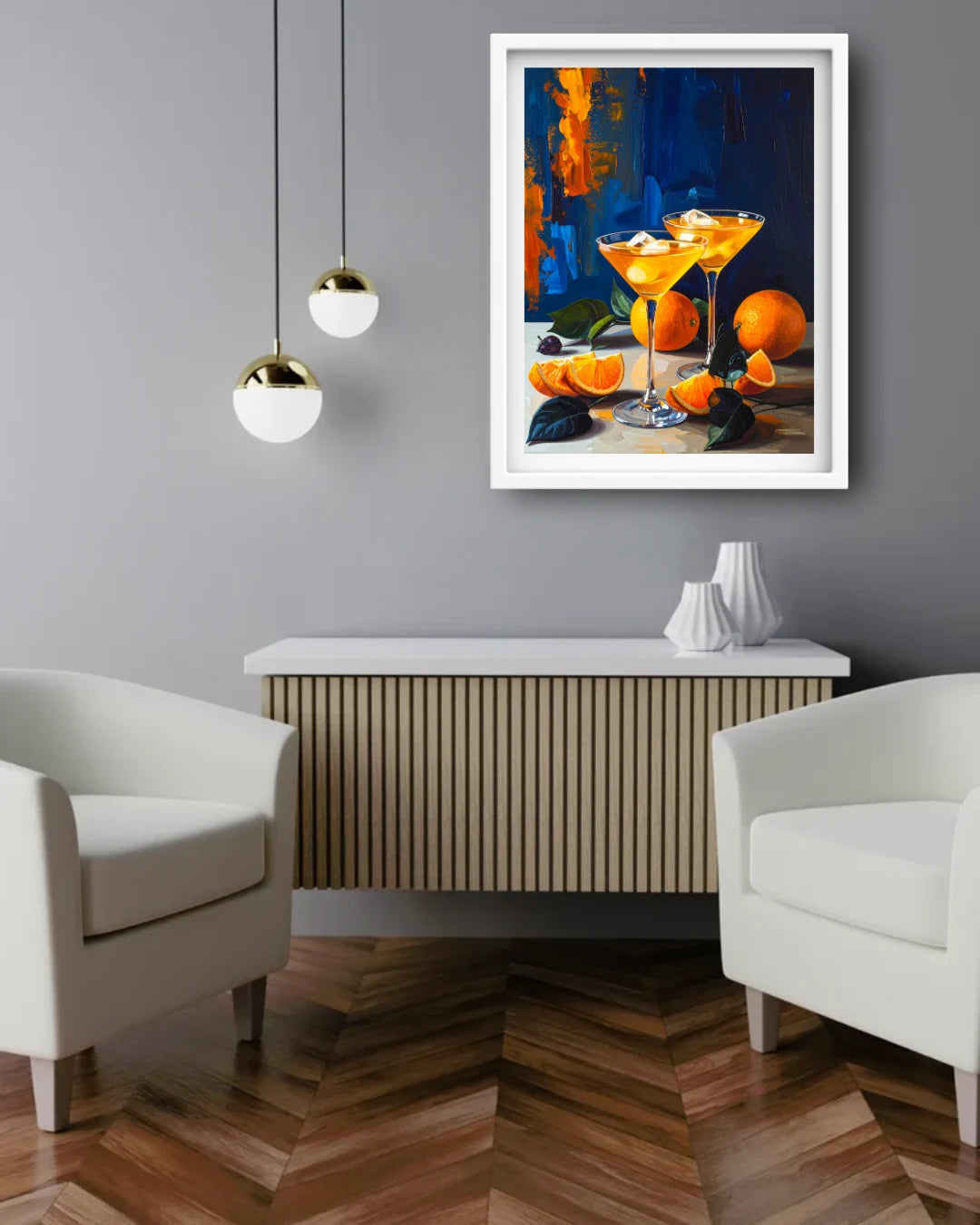 A framed art print depicting two orange cocktails and oranges on a dark blue background, displayed on a gray wall above a modern wooden console table in a styled living room setting.