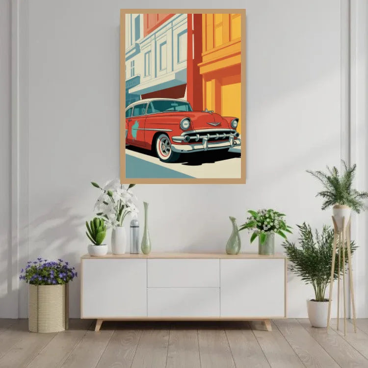 A framed art print featuring a retro red classic car in a stylized street scene, displayed on a white wall above a modern white sideboard with decorative plants and vases.