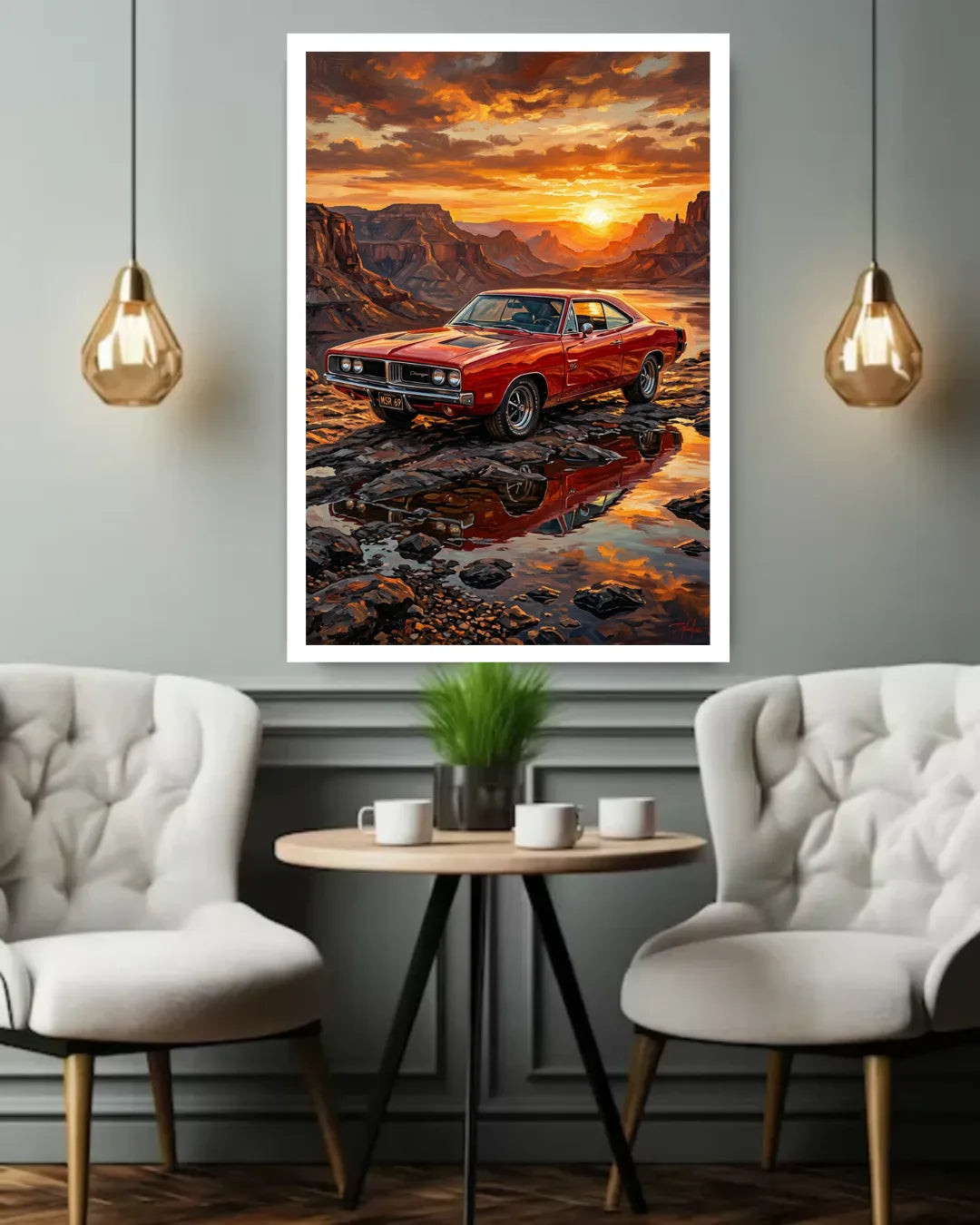 A framed wall art print showing a red muscle car parked in a rocky riverbed at sunset, displayed above a small round table between two white tufted chairs in a modern room.