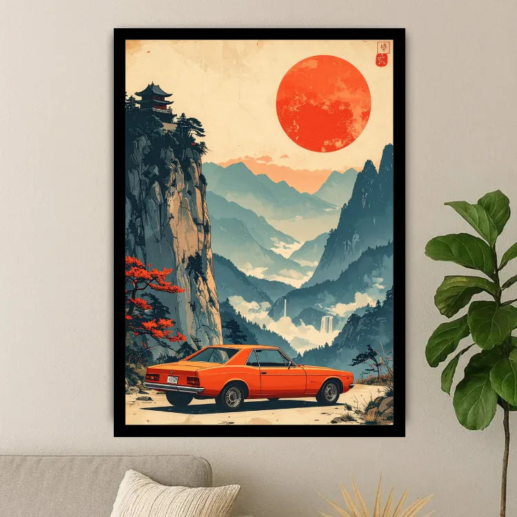A framed art print featuring a retro orange car parked in a scenic mountain landscape with a large red sun, displayed on a light gray wall above a sofa with a potted plant nearby.