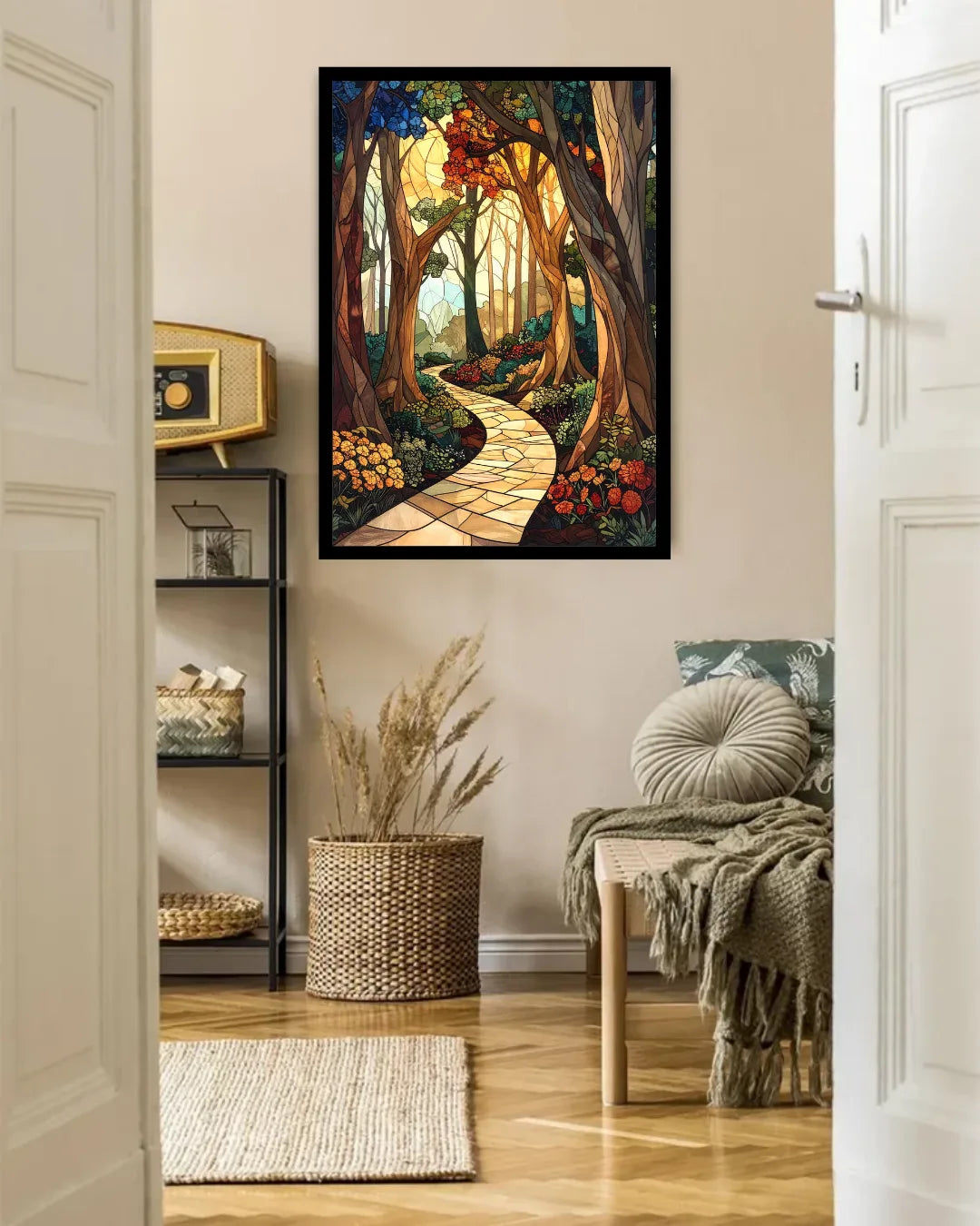 A framed vertical art print depicting a winding stone path through a sunlit forest, displayed on a beige wall in a styled room with a chair, basket, and shelving.