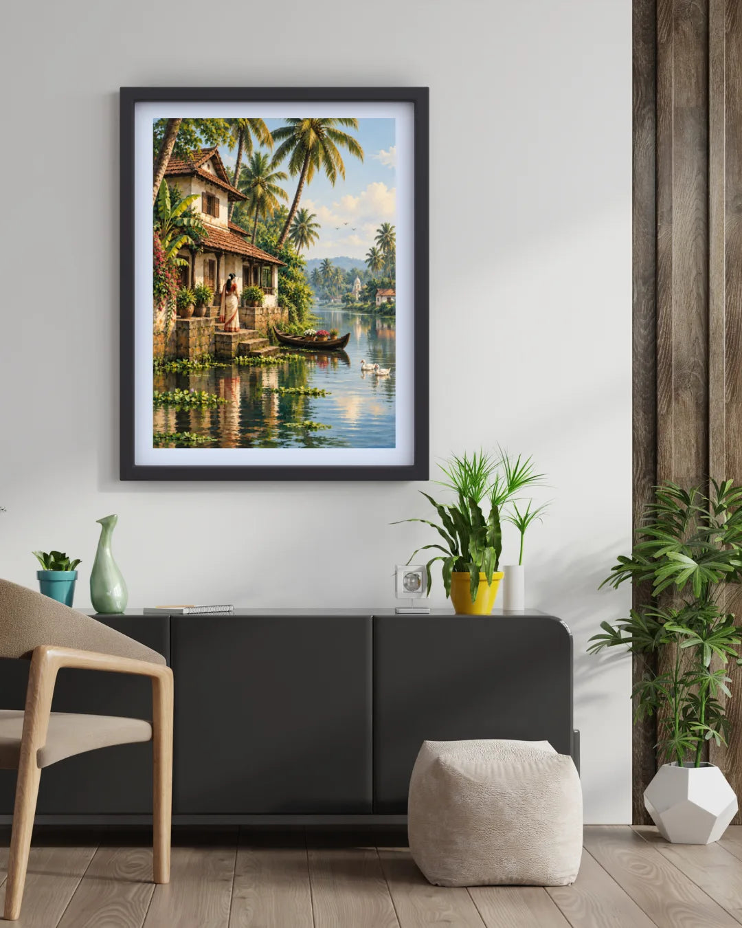 A framed art print depicting a tropical lake scene with palm trees, a house, and a boat, displayed on a white wall above a dark gray sideboard in a modern living room setting.