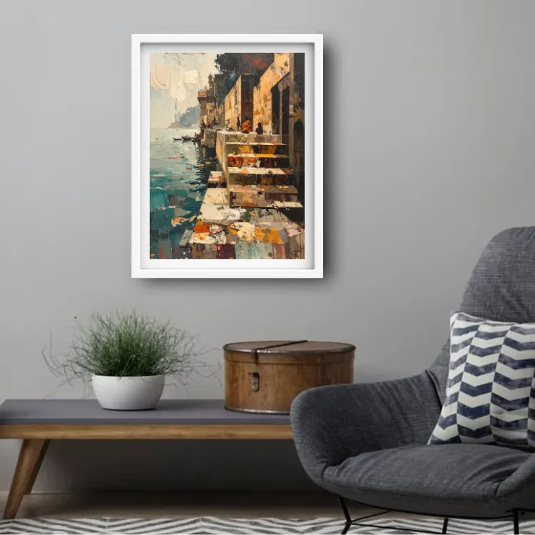 A framed vertical painting of an impressionistic waterfront scene with warm-toned buildings and blue-green water, displayed on a gray wall above a console table in a styled living room setting.
