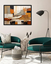 An abstract framed wall art print with geometric blocks in beige, orange, brown, black, and gray, displayed in a modern living room setting above two teal armchairs.