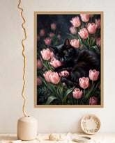 Black cat sleeping among pink tulips in a beige-framed floral canvas painting displayed on a cream wall.