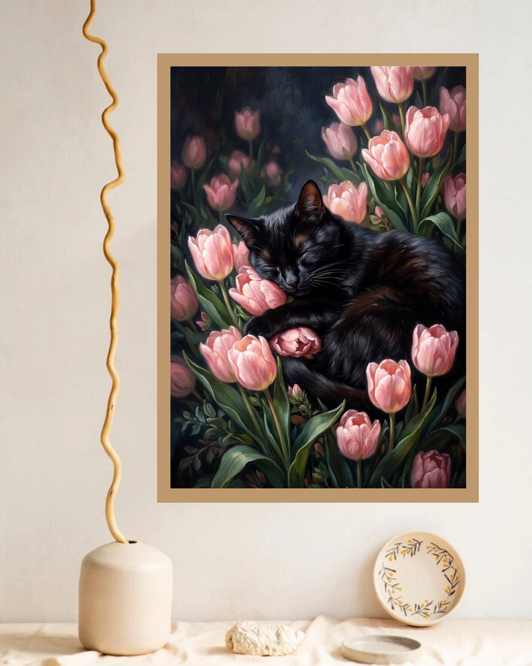 Black cat sleeping among pink tulips in a beige-framed floral canvas painting displayed on a cream wall.