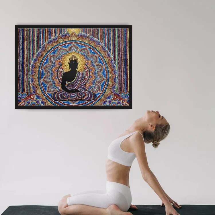 A woman in white activewear poses on a yoga mat in a studio, with a large framed colorful Buddha mandala print hanging on the wall above her.