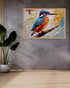 Colorful painting of a kingfisher on a wall with a plant below.