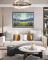 Modern living room with a sofa, coffee table, and wall art of a forest scene.