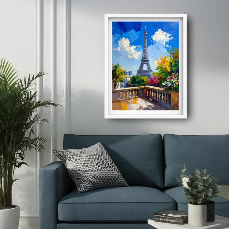 A framed colorful painting of the Eiffel Tower in Paris, displayed on a light gray wall above a blue sofa in a modern living room setting.