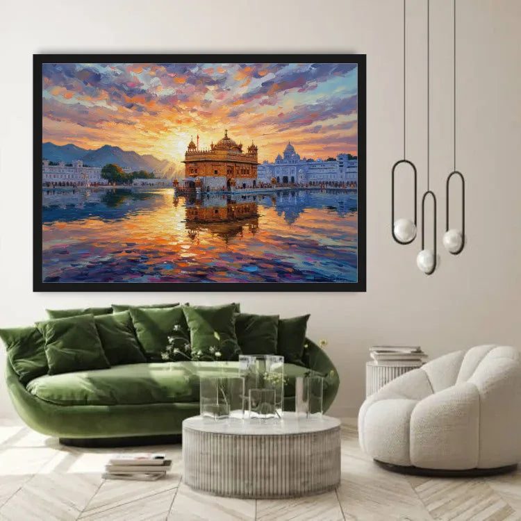 A large framed canvas print of the Golden Temple in Amritsar, depicted at sunset with vibrant orange, yellow, and blue sky reflections, displayed on a beige wall in a modern living room setting above a green velvet sofa.