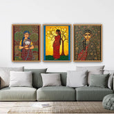 Three framed artworks of women in traditional attire on a wall above a gray sofa.