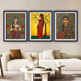 Three framed artworks of women in traditional attire on a wall above a white sofa.