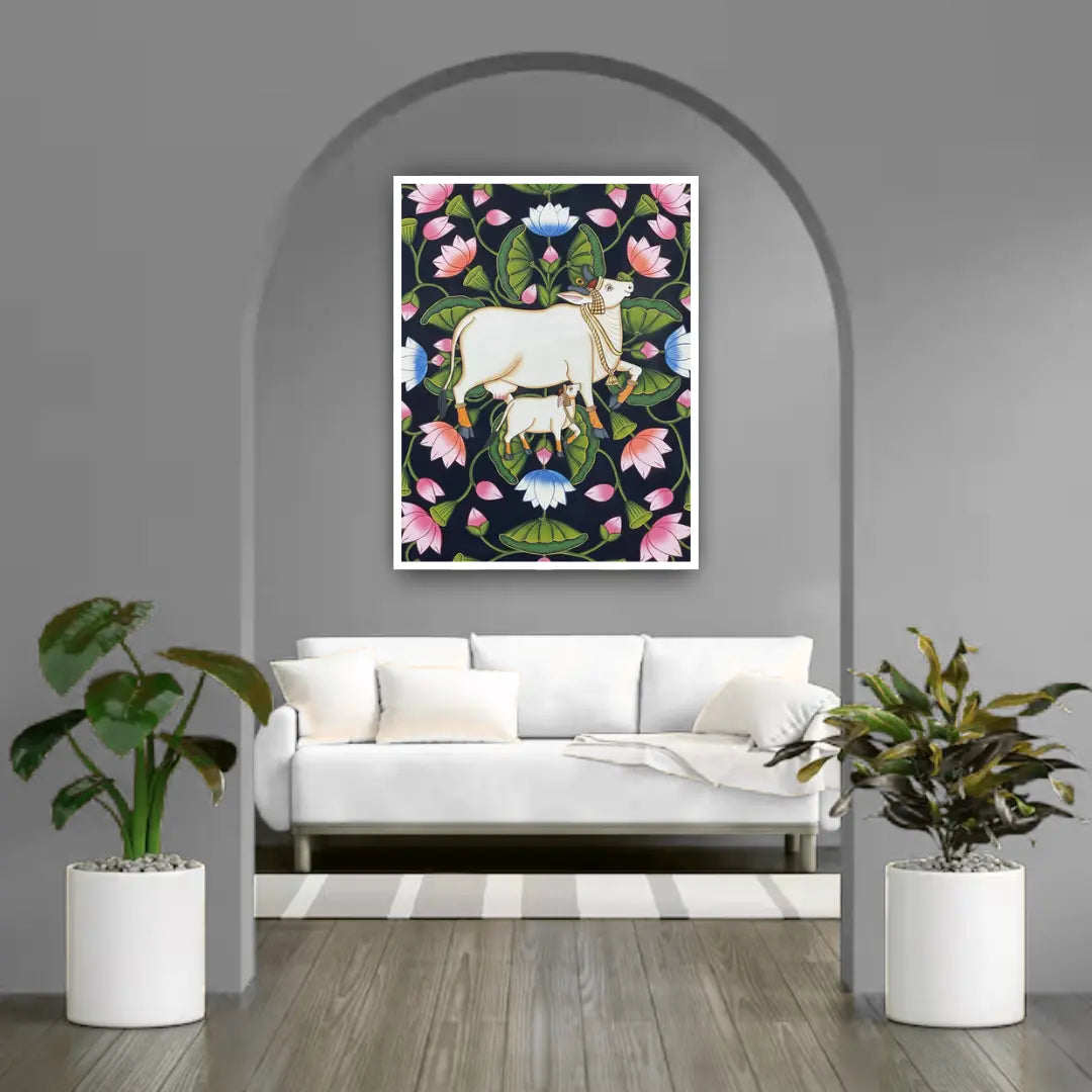 Living room with a white sofa, decorative plants, and a framed artwork of cows and flowers on the wall.