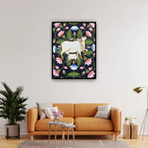 Living room with an orange sofa, decorative plant, and a framed artwork of a cow among flowers on the wall.