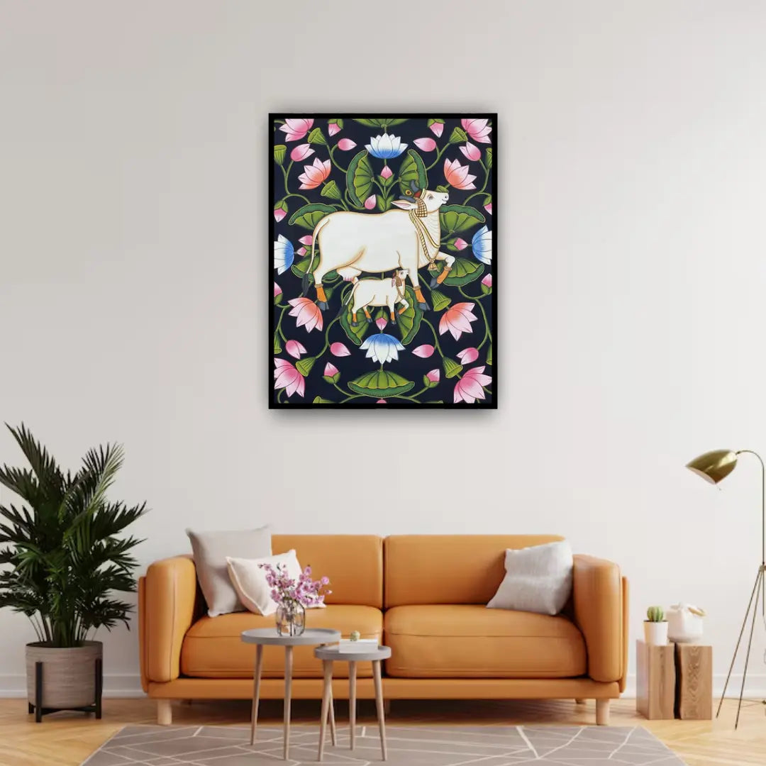 Living room with an orange sofa, decorative plant, and a framed artwork of a cow among flowers on the wall.