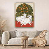 Framed artwork of two cows under an orange tree in a living room setting.