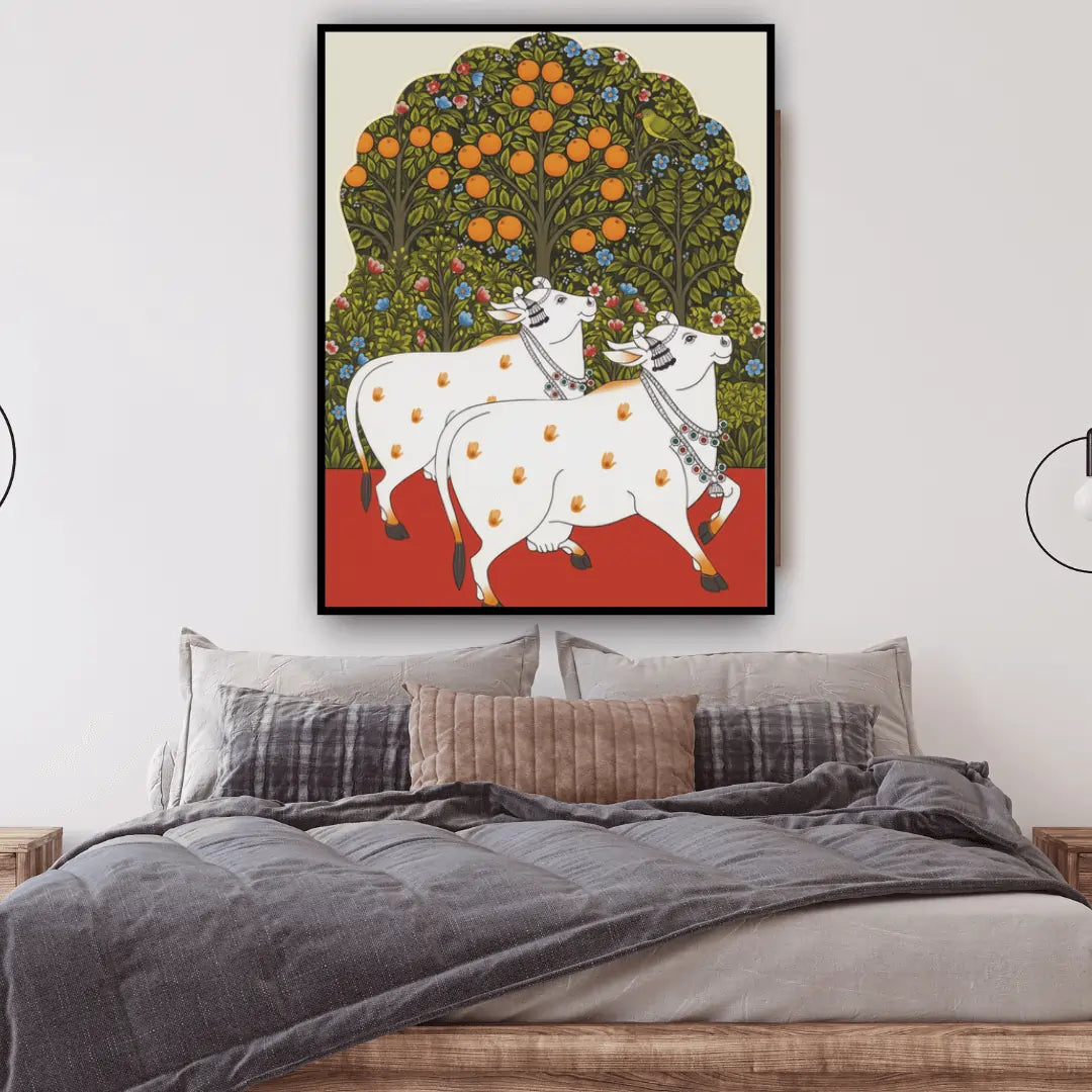 Framed artwork of two cows under an orange tree above a bed with gray bedding.
