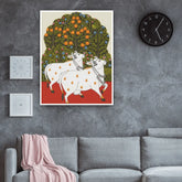Decorative wall art of two white cows under an orange tree in a living room.