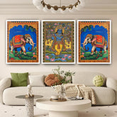 Three colorful framed artworks of elephants and a deity on a wall above a sofa.