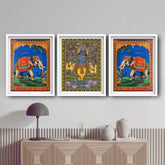 Three colorful framed artworks of elephants and deities on a wall above a cabinet.