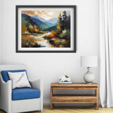 A framed landscape painting of a mountain river scene with autumn foliage, displayed on a white wall above a wicker armchair and a wooden side table with a lamp.