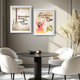 Two framed wall art prints hanging above a round black table with white chairs in a modern room. The left print shows an espresso-themed guitar illustration with the text &