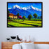 A framed landscape art print depicting snow-capped mountains, green fields, trees, and a small house, displayed on a light gray wall above a wooden headboard with white pillows and decorative vases.