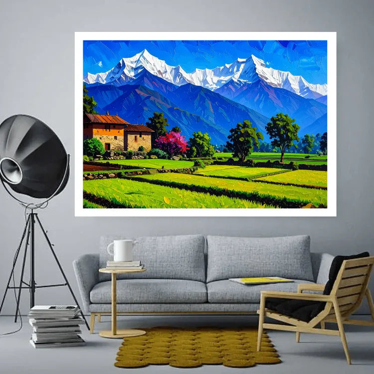 A framed art print depicting a vibrant mountain landscape with snow-capped peaks, green fields, and a small house, displayed on a gray wall above a modern gray sofa in a styled living room.