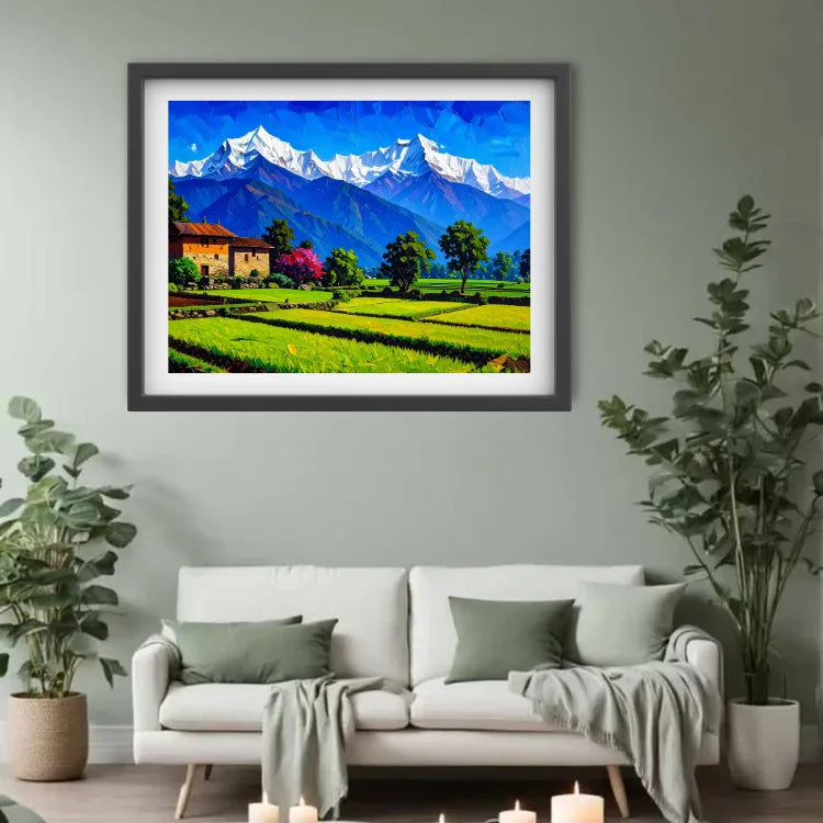 A framed landscape painting of snow-capped mountains, green fields, and a small house, displayed on a light gray wall above a white sofa with plants on both sides.