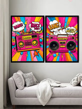 Two framed pop-art posters featuring retro boomboxes and comic-style speech bubbles hang above a light gray sofa in a living room setting.