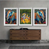 Three framed artworks of elephants and a couple on a wall above a wooden cabinet.
