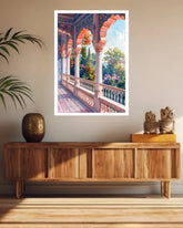 A framed art print depicting a colorful traditional archway balcony with lush greenery and pink flowers, displayed on a beige wall above a wooden console table in a styled room.