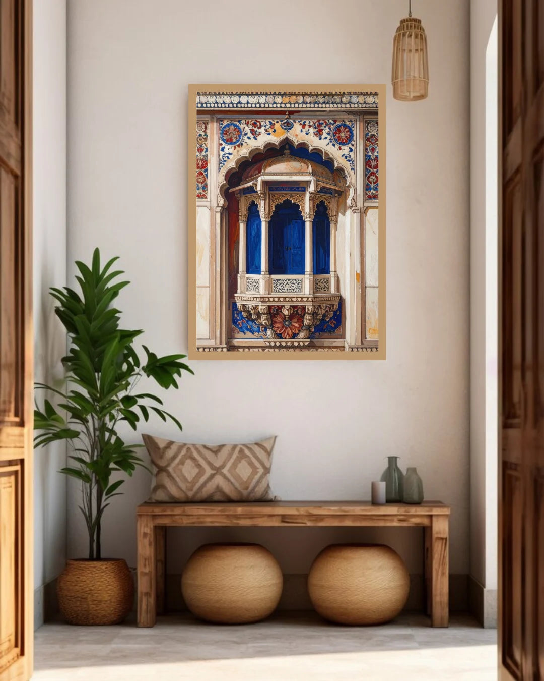 A framed art print depicting a traditional Indian Rajasthani chikankari jharoka arch with vibrant blue and gold details, displayed on a beige wall in a styled entryway with a wooden bench, potted plant, and woven decor.