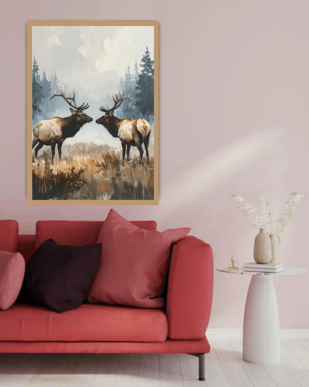 Framed artwork of two elk on a wall above a red sofa with pink cushions.