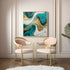 Teal and gold abstract canvas painting displayed in a modern living space with pastel seating chairs.