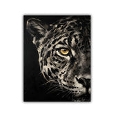 A square canvas art print featuring a close-up portrait of a leopard or snow leopard with striking yellow eyes against a dark background, shown on a plain white studio backdrop.